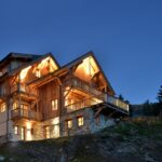 Vue saisissante du chalet tout éclairé de nuit qui met en valeur l'architecture.