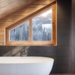 Salle de bain avec vue sur l'extérieur, baignoire sabot et ambiance boisée et luxe.